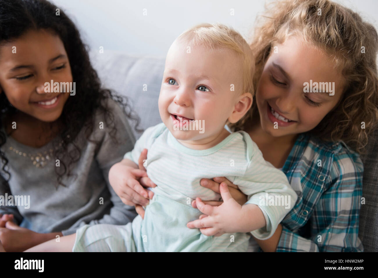 Freund beobachten lächelndes Mädchen hält Baby Bruder Stockfoto
