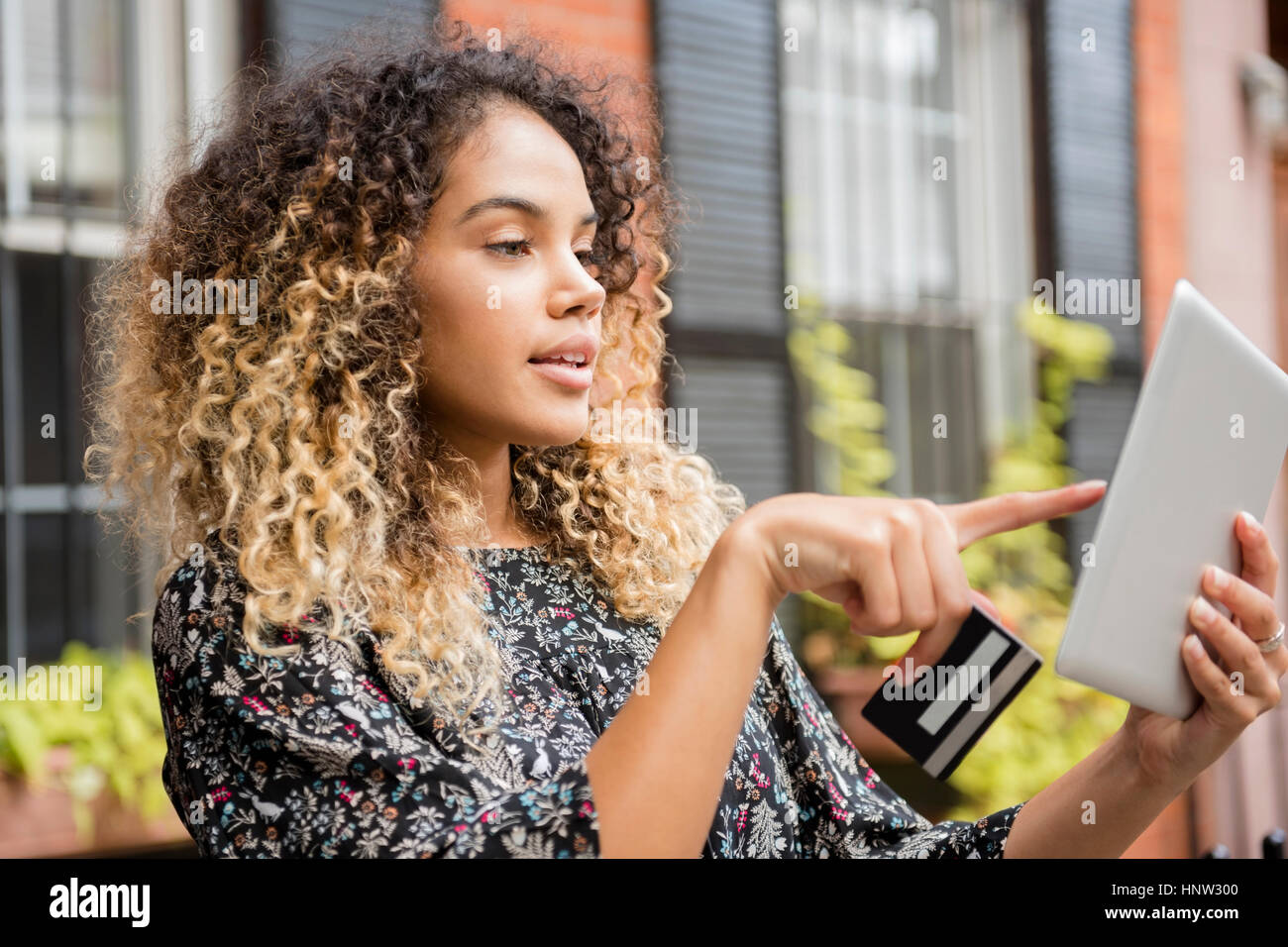 Gemischte Rennen Frau online-shopping mit digital-Tablette in Stadt Stockfoto