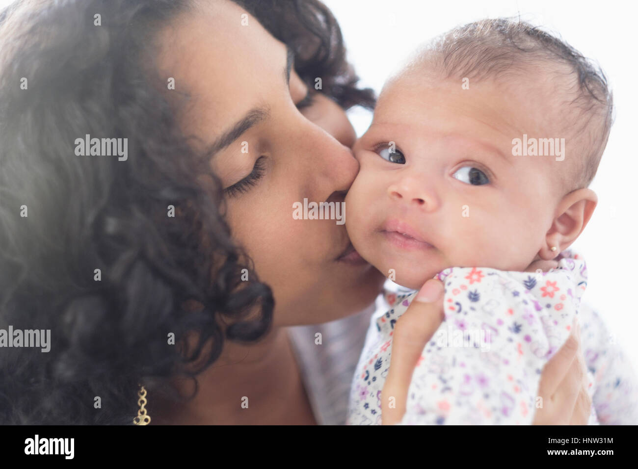 Hispanische Mutter Tochter auf Wange küssen Stockfoto