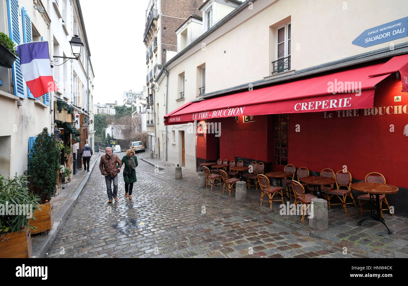 Montmartre, Paris. zwei Menschen gehn durch eine gepflasterte Straße in Montmartre Village, Paris Stockfoto