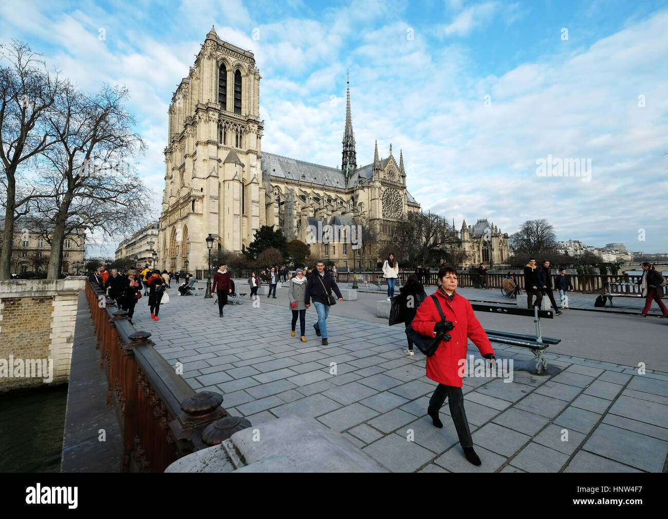 Eine Frau in rot zu Fuß mit Notre Dame de Paris; La Cathédrale Notre-Dame de Paris in der Ferne. Stockfoto