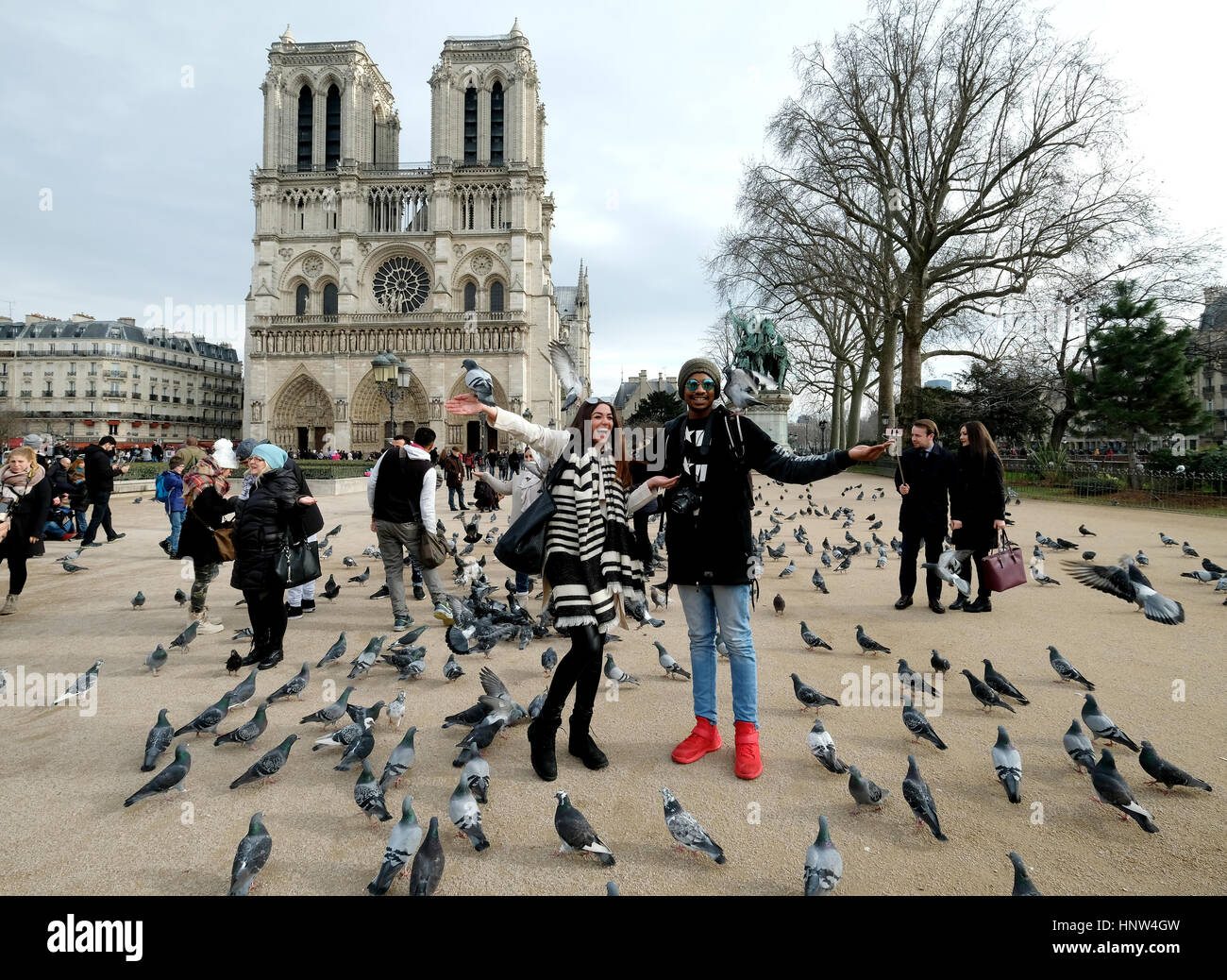 Ein junges Paar für Bilder darstellen, wie sie füttern Tauben vor der Notre Dame Kathedrale in Paris, Frankreich Stockfoto
