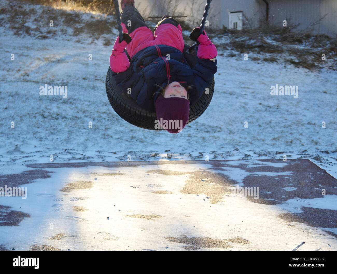 Ein kleines Mädchen auf einem reifen Schwingen im Winter. Stockfoto