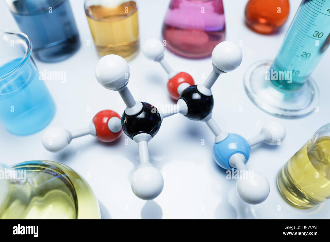 Chemie-Forschung. Ball-und-Peitsche-Molekülmodell umgeben von verschiedenen Fläschchen mit Übergangsmetall-Salze Lösungen Stockfoto