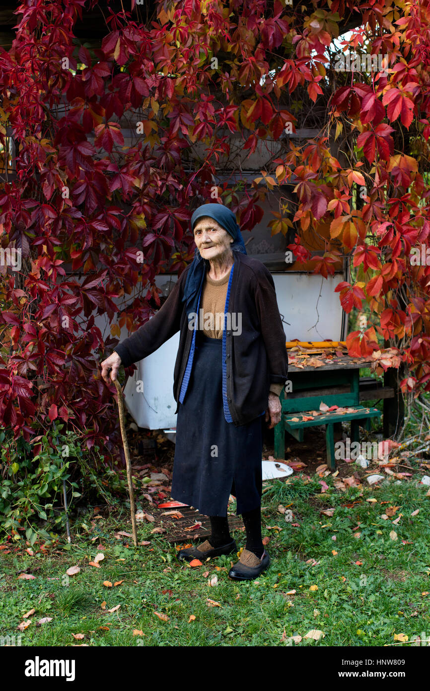 Porträt von senior Woman Walking Stick stehen im Herbst Garten Stockfoto