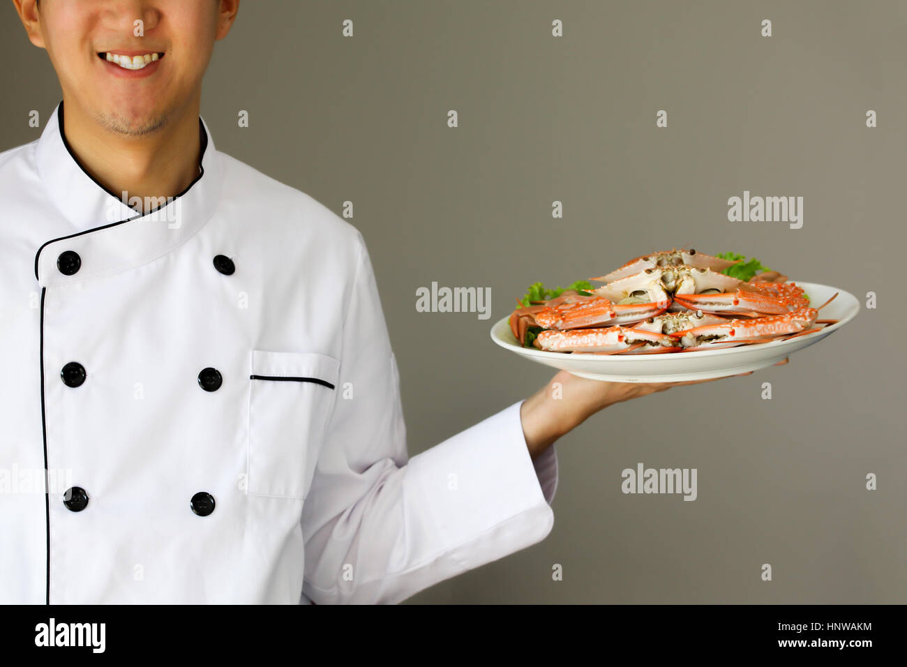 Küchenchef präsentiert mit Stolz und glücklich lächelnd Krabben auf dem Teller gedämpft Stockfoto