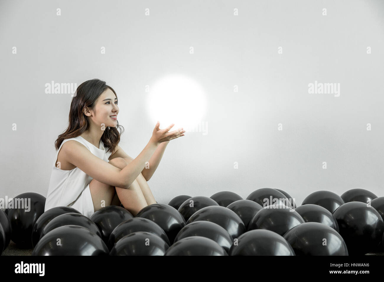 Junge Frau mit weißen Ballon sitzen im schwarzen Stockfoto