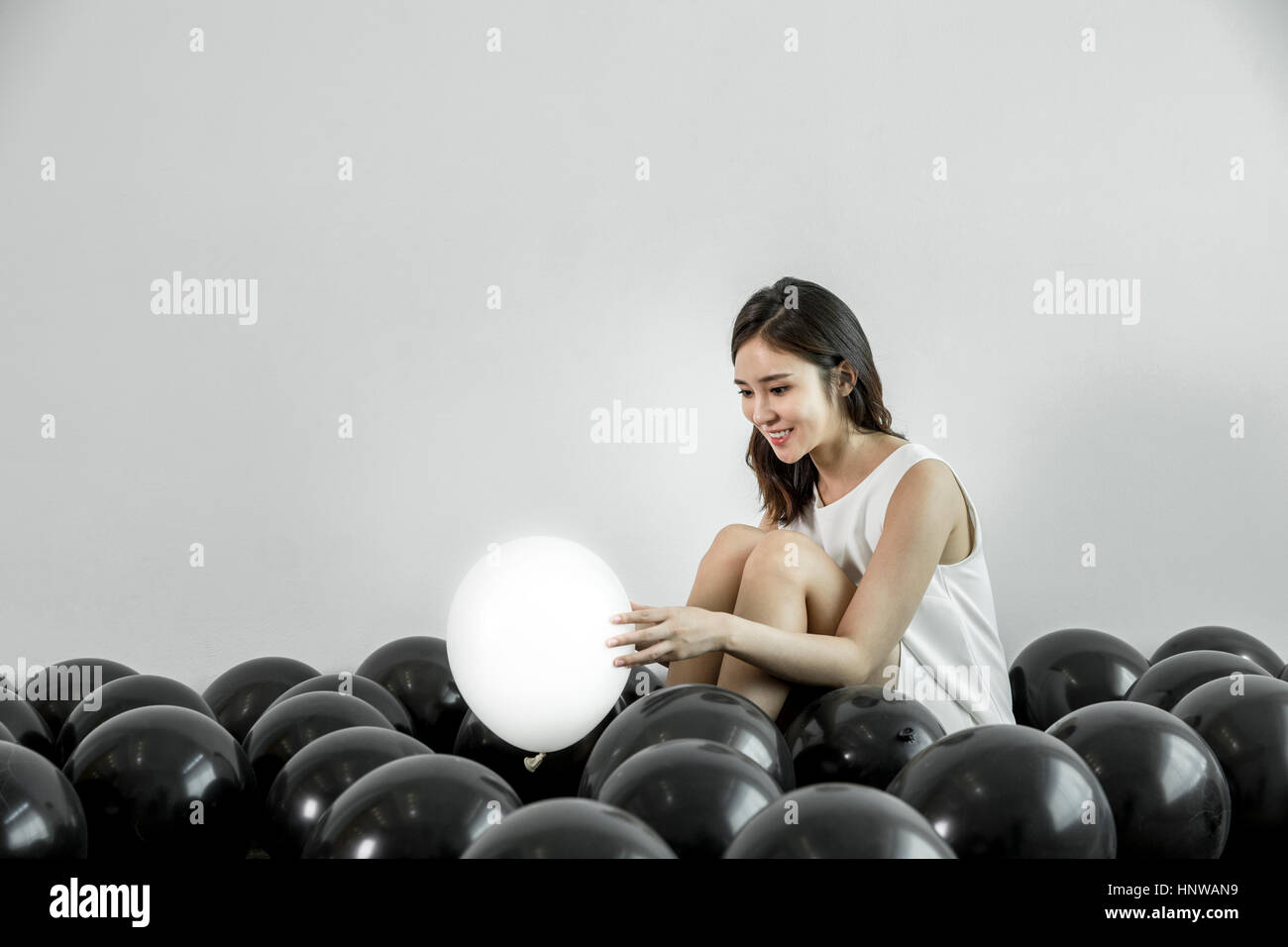 Junge Frau zu finden, weiße Ballon unter schwarzen Stockfoto