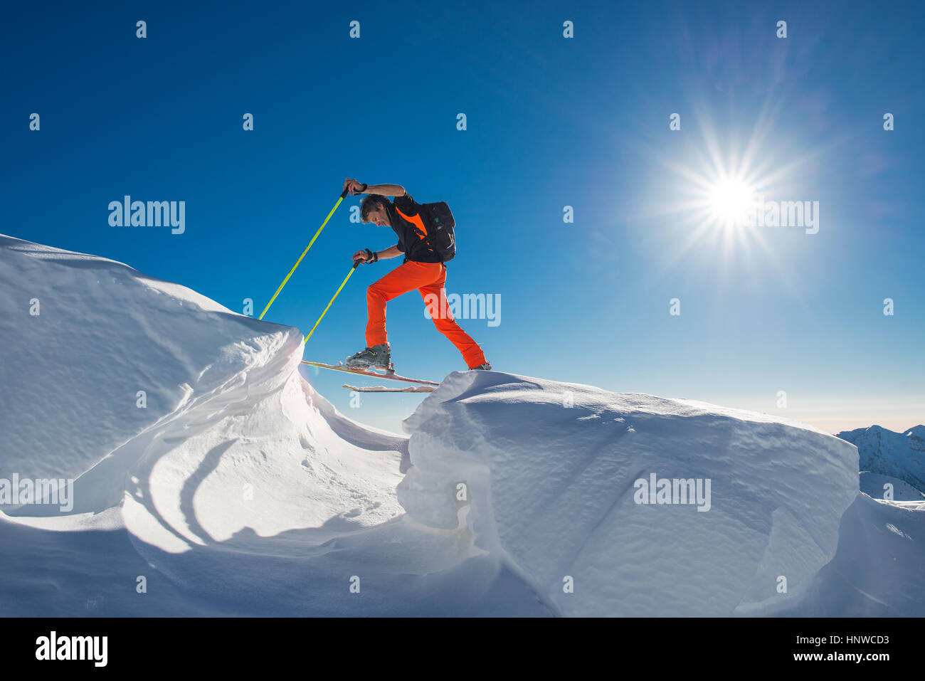 Ein Mann Skirennläufer Klettern auf Skiern und Fellen in so viel Schnee mit Hindernissen im Una Giornata di sole forte Stockfoto