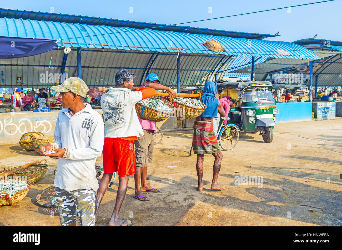 NEGOMBO, SRI LANKA - 25. November 2016: Zwei Arbeiter tragen die Fische in Körben auf dem Stick in Tuk Tuk für Großhandel Käufer am 25 November im Laden Stockfoto