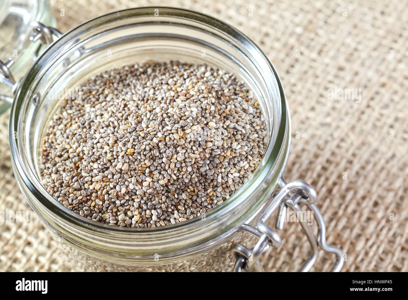 Nahaufnahme von Chia-Samen in einem Glas auf Leinen Hintergrund, Lebensmittel reich an Omega-3-Fettsäuren. Stockfoto