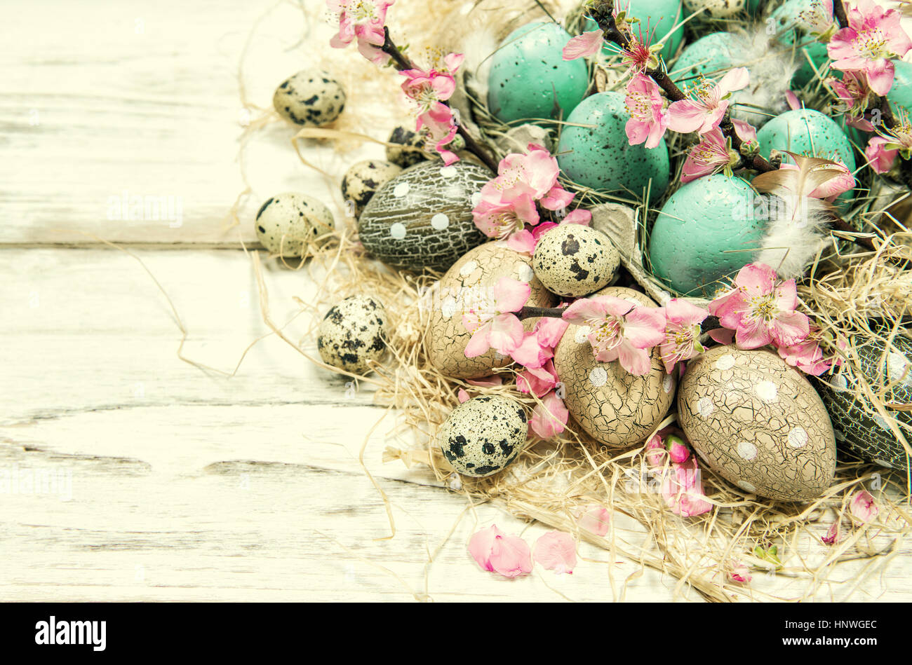 Oster-Deko mit blauen Eiern und rosa Blüten. Vintage-Stil getönten Bild Stockfoto