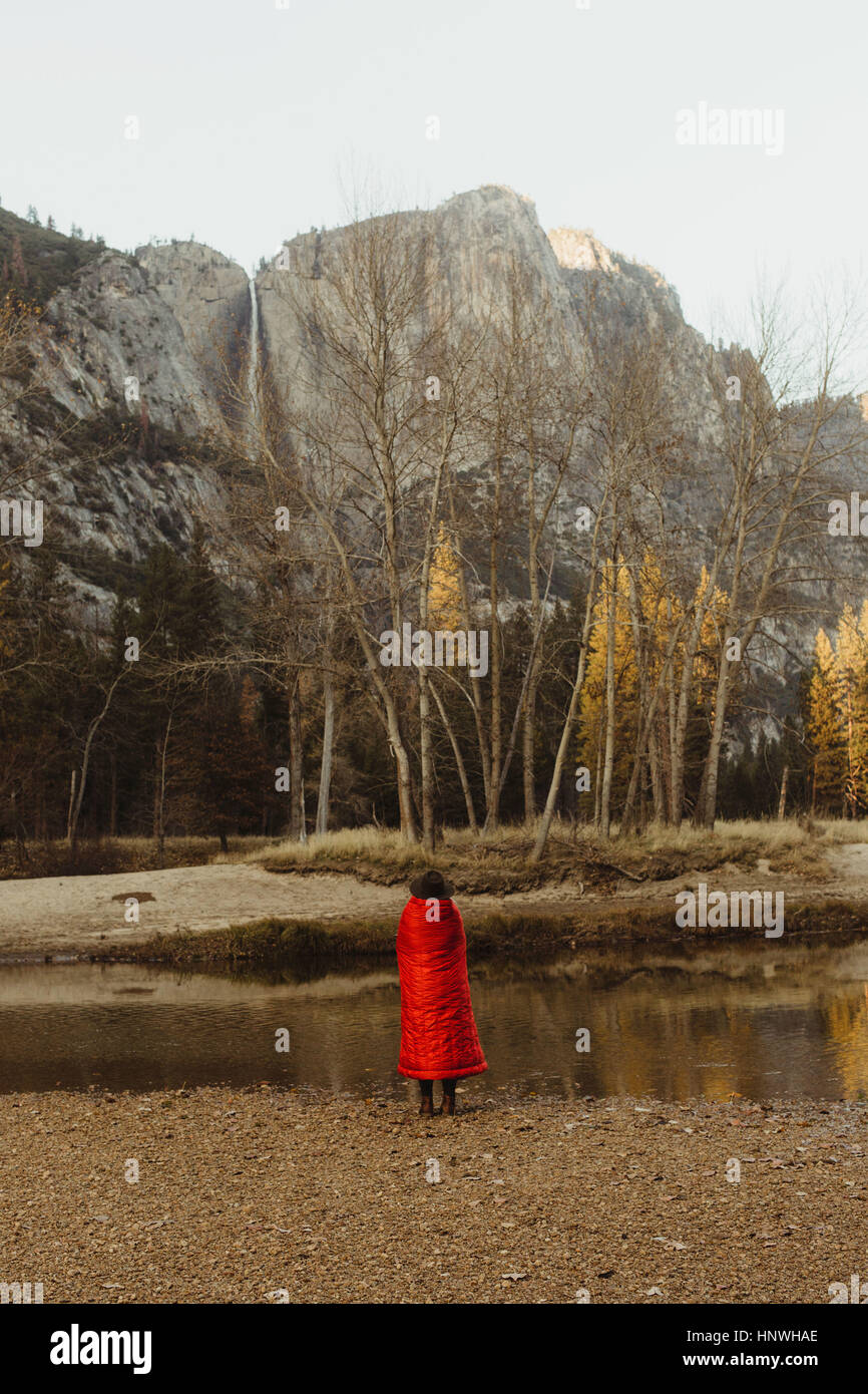 Rückansicht des Frau eingewickelt in rote Decke mit Blick auf Berg, Yosemite-Nationalpark, Kalifornien, USA Stockfoto