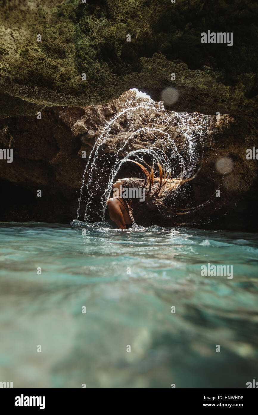Frau im Wasser gefüllte Höhle werfen wieder nasses Haar, plantschen, Oahu, Hawaii, USA Stockfoto