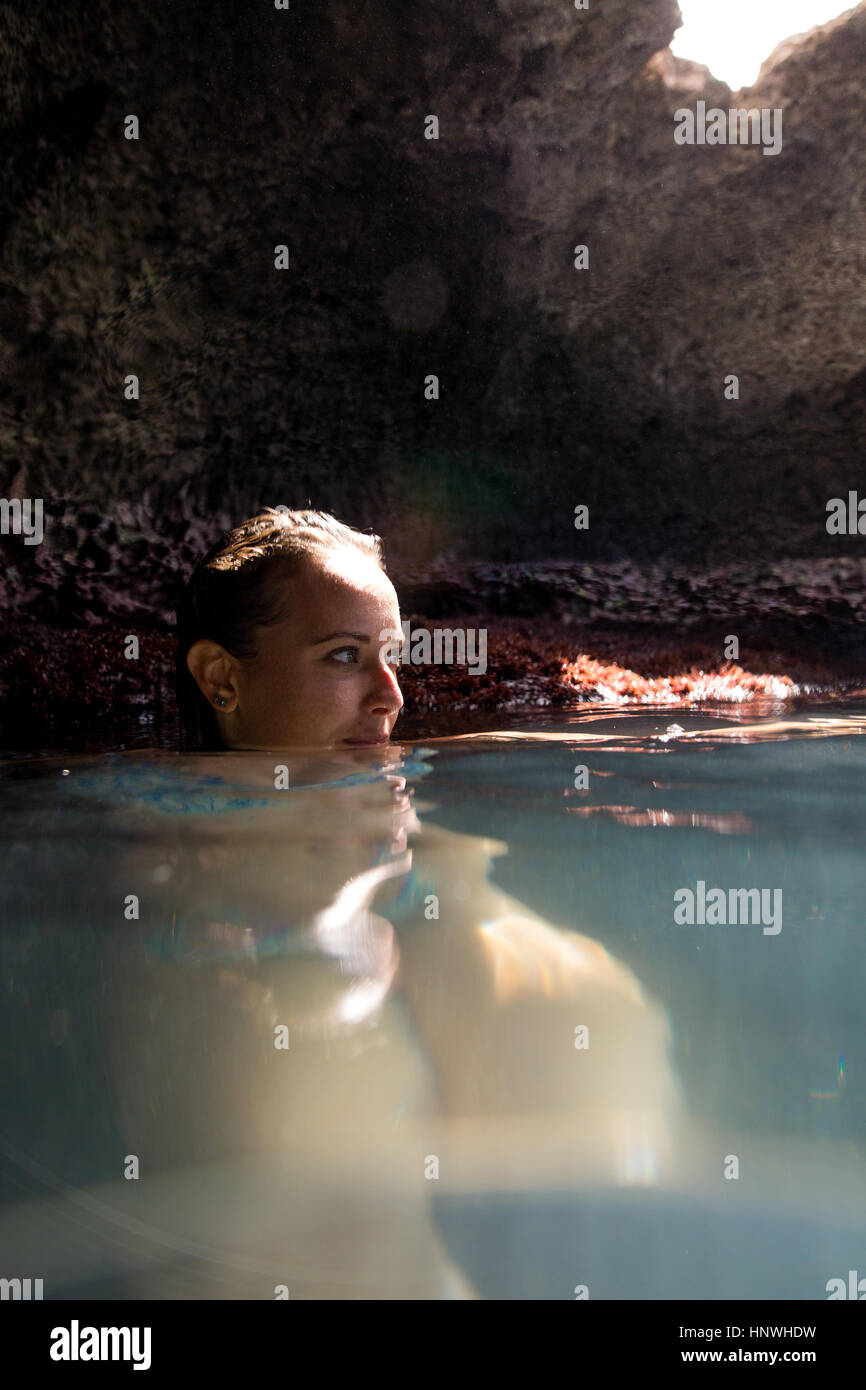 Frau im Wasser gefüllte Höhle wegsehen, Oahu, Hawaii, USA Stockfoto