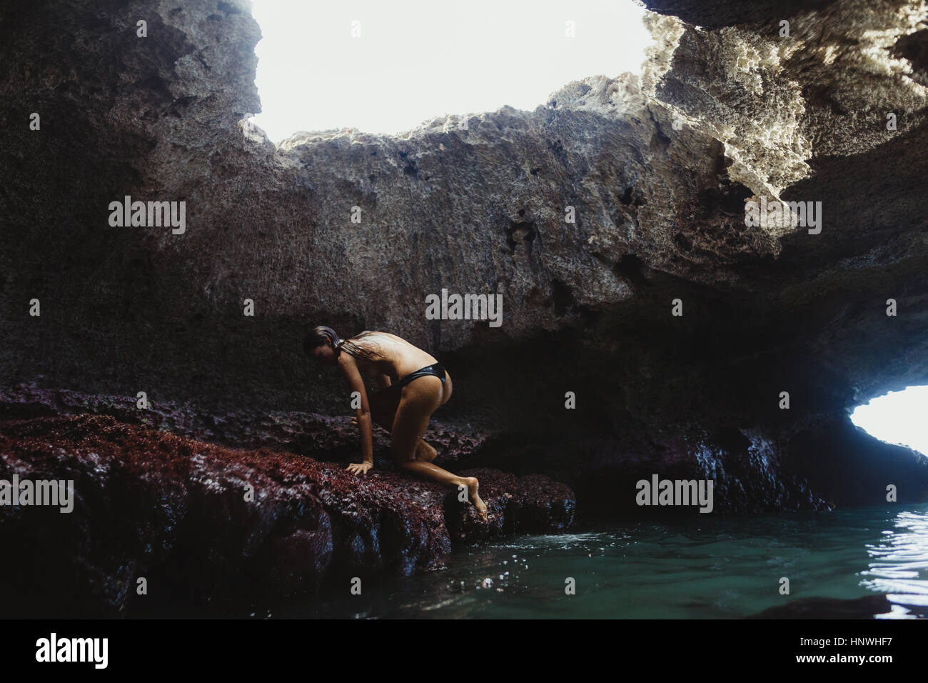 Junge Frau Klettern auf Felsen, Meerjungfrau Höhlen, Oahu, Hawaii, USA Stockfoto