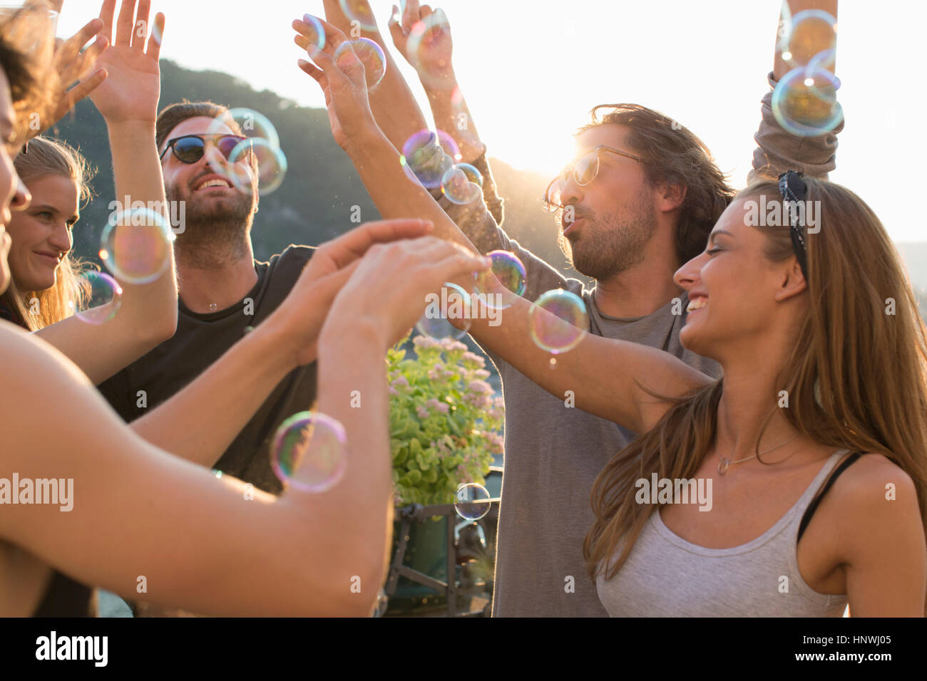 Erwachsene Freunde feiern mit schwimmenden Seifenblasen auf Dachterrasse Stockfoto