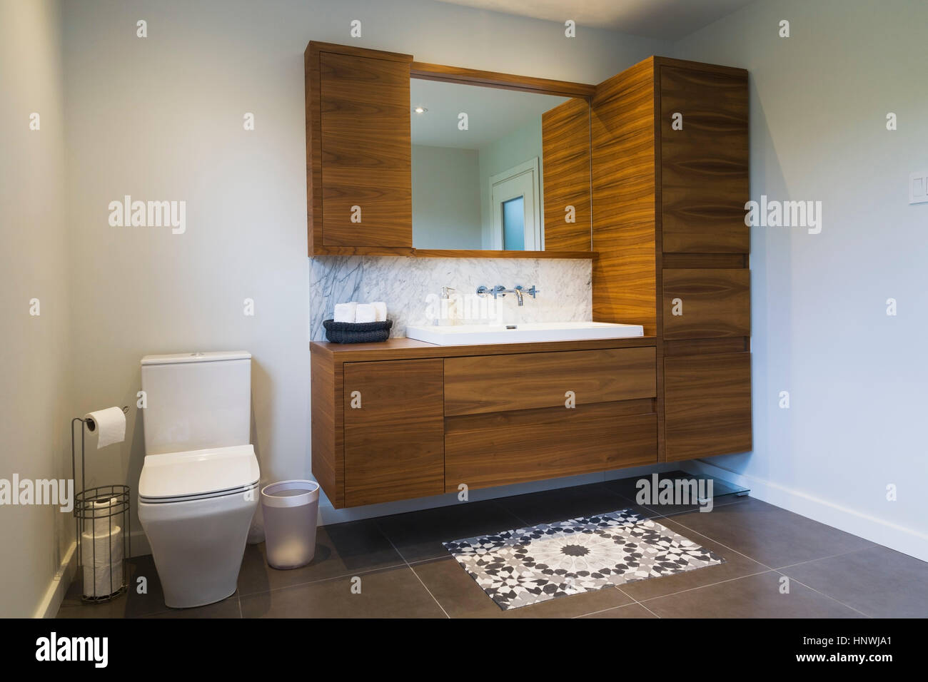 Weiße Toilette mit Wasserspülung hohem Rücken und amerikanischem Nussbaum Holz Waschtisch mit rechteckigen Waschbecken und Keramik-Fliesen-Böden, Quebec, Kanada Stockfoto