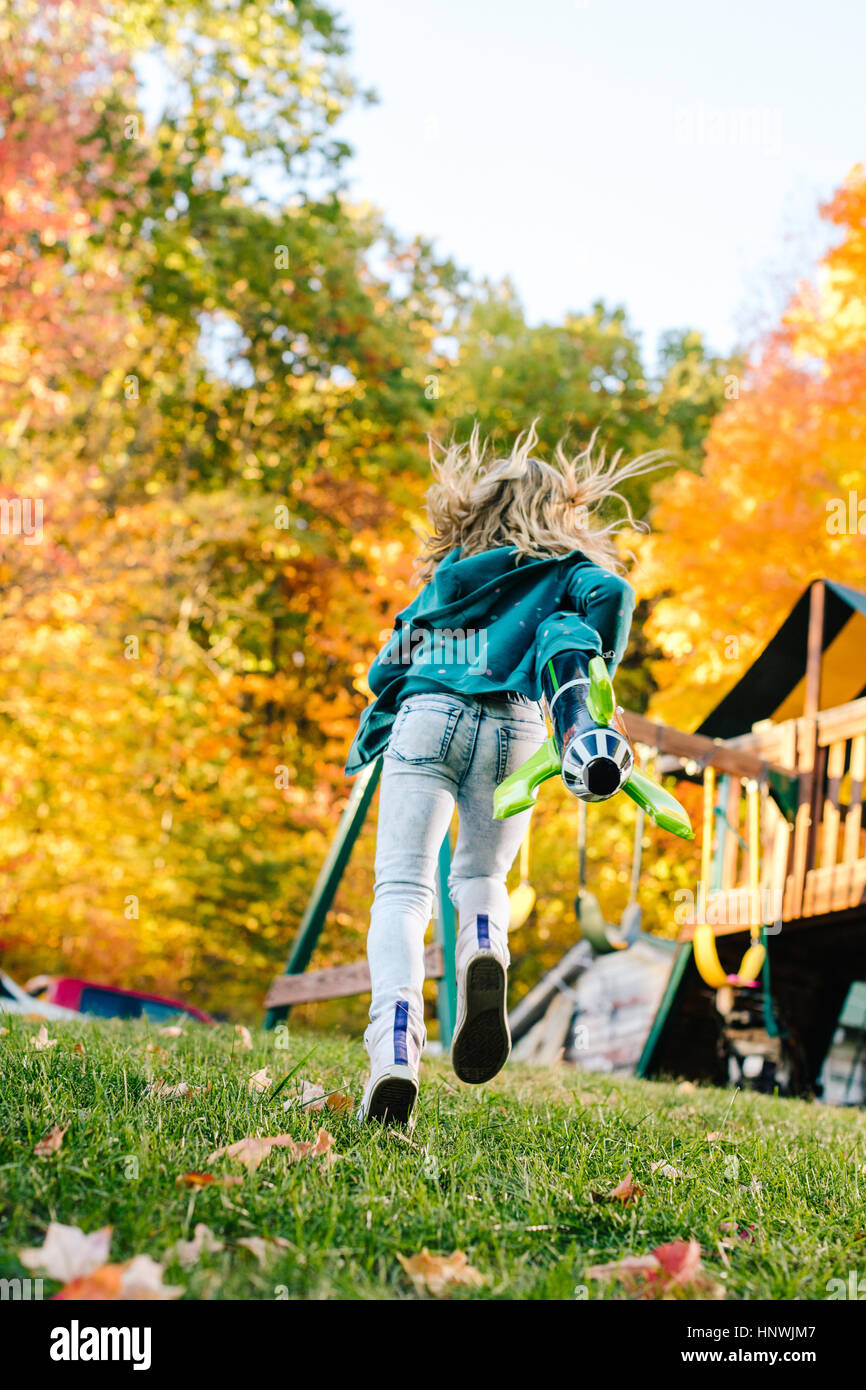 Rückansicht des Mädchen laufen mit Spielzeug Rakete im Garten Stockfoto