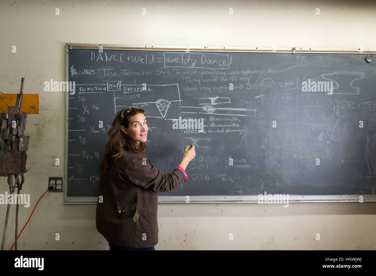 Weibliche Metallarbeit Lehrer schreiben an Klassenzimmer Tafel Stockfoto