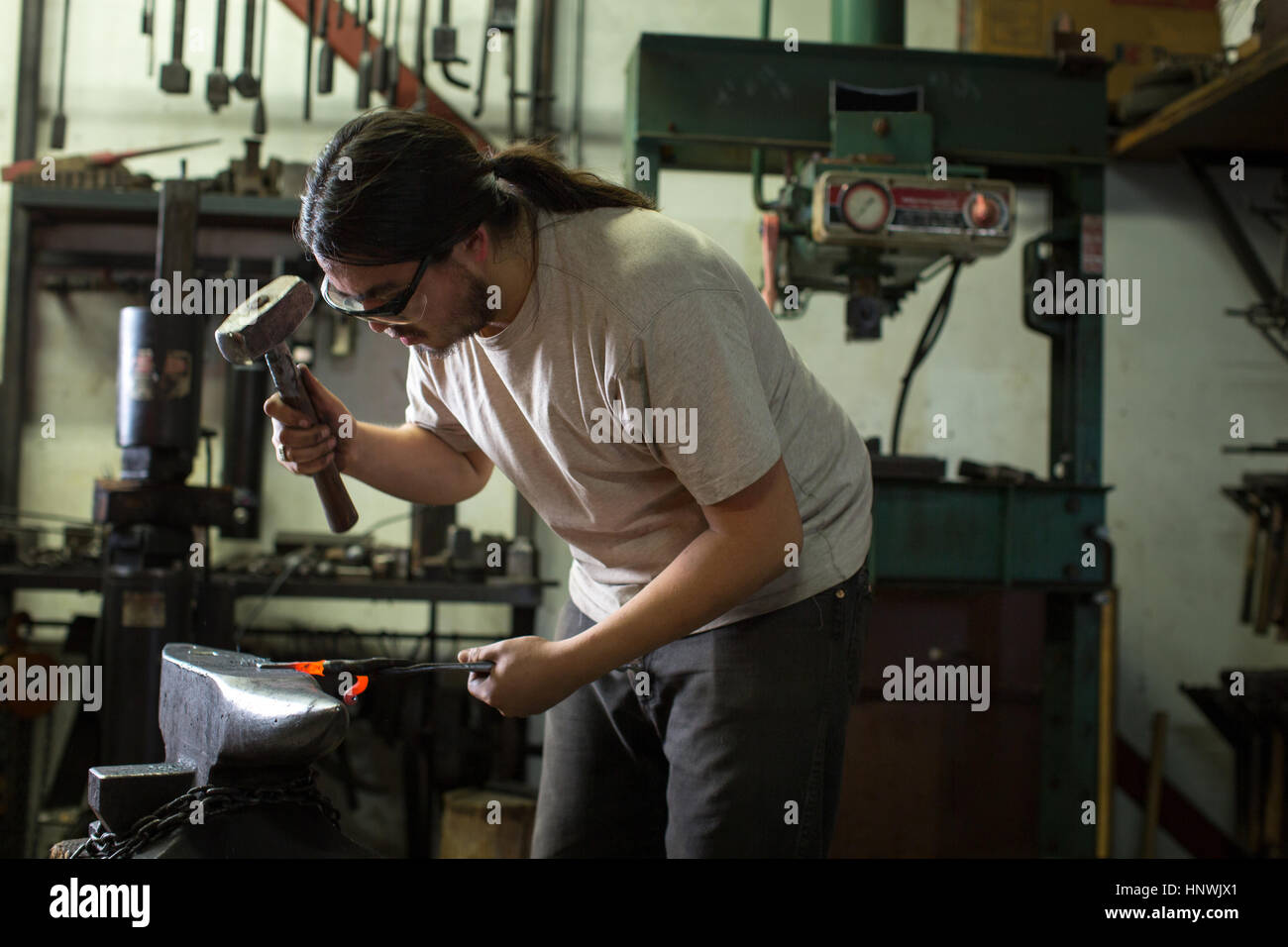 Männlichen Schmied Hämmern rote Roheisen auf Workshop-Amboss Stockfoto