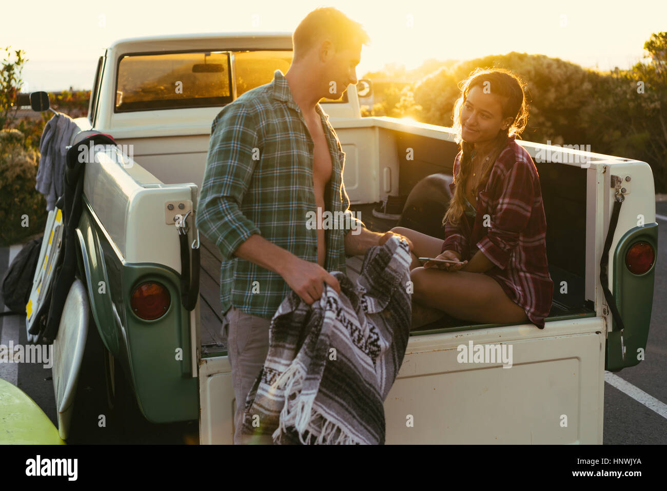 Surfen-paar auf der Rückseite Pickup-Truck bei Sonnenuntergang in Newport Beach, Kalifornien, USA Stockfoto