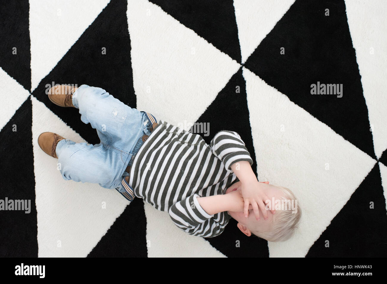 Junge auf Boden liegend, für Augen, erhöht, Ansicht Stockfoto