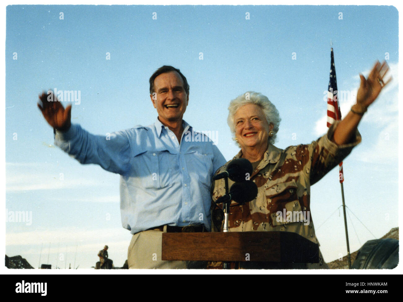 Präsident George Bush und First Lady Barbara Bush Welle, wie sie auf der Rückseite eines Fahrzeugs bei einem Besuch in einem einsamen Lager stehen. Der Präsident und seine Frau zahlen Erntedankfest Besuche von US-Truppen, die in Saudi Arabien für Operation Desert Shield. 1990 Stockfoto