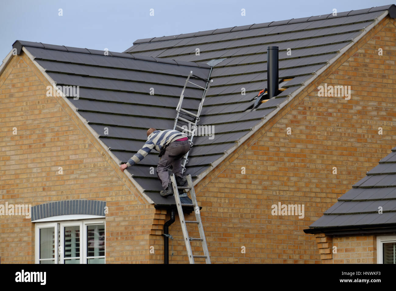 Arbeiter auf einem Hausdach installieren einen Schornstein Stockfoto