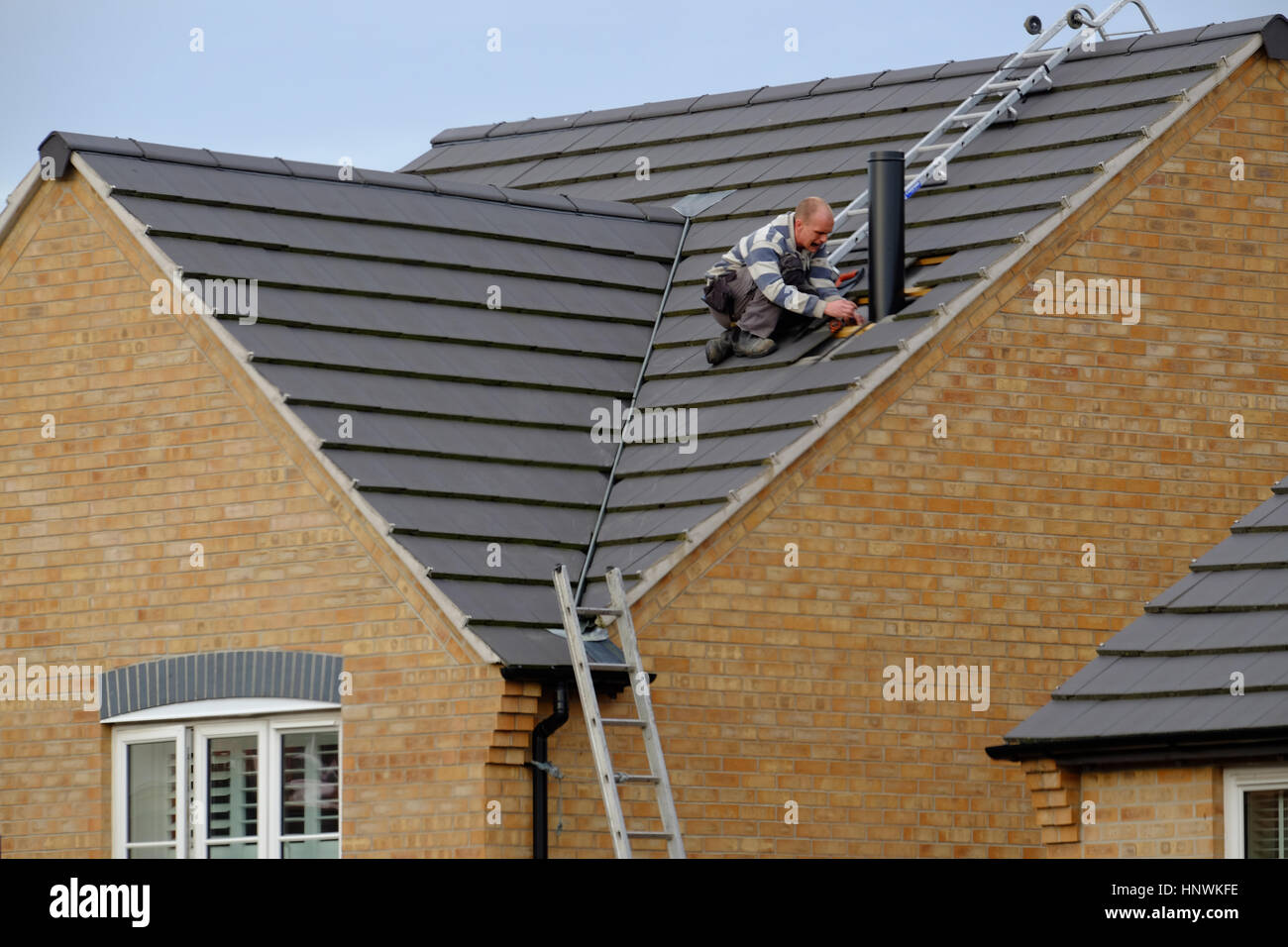 Arbeiter auf einem Hausdach installieren einen Schornstein Stockfoto