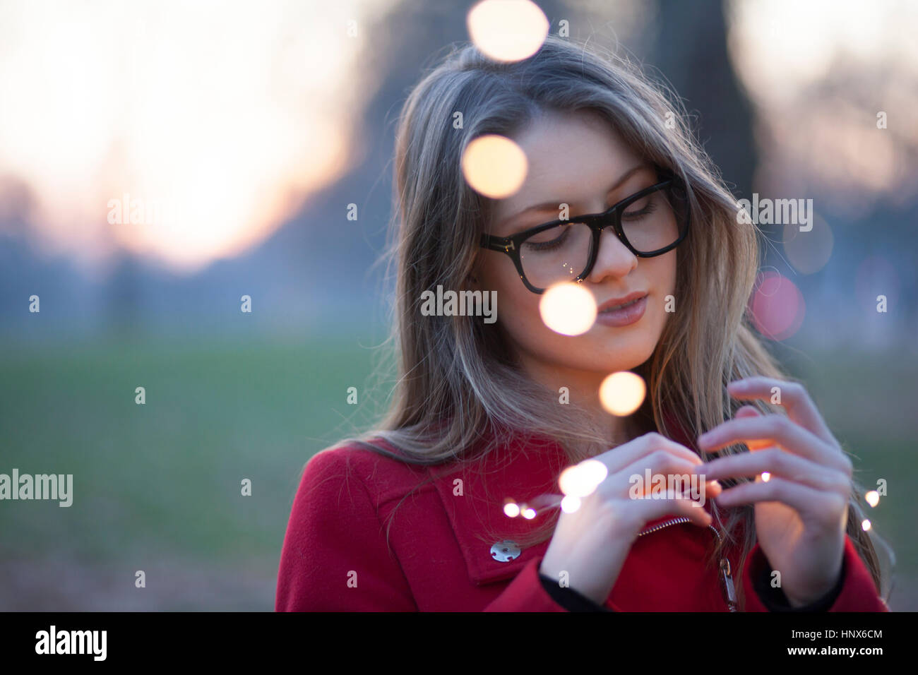 Junge Frau im Park Blick auf Lichter in ihrer Hand, London, UK Stockfoto