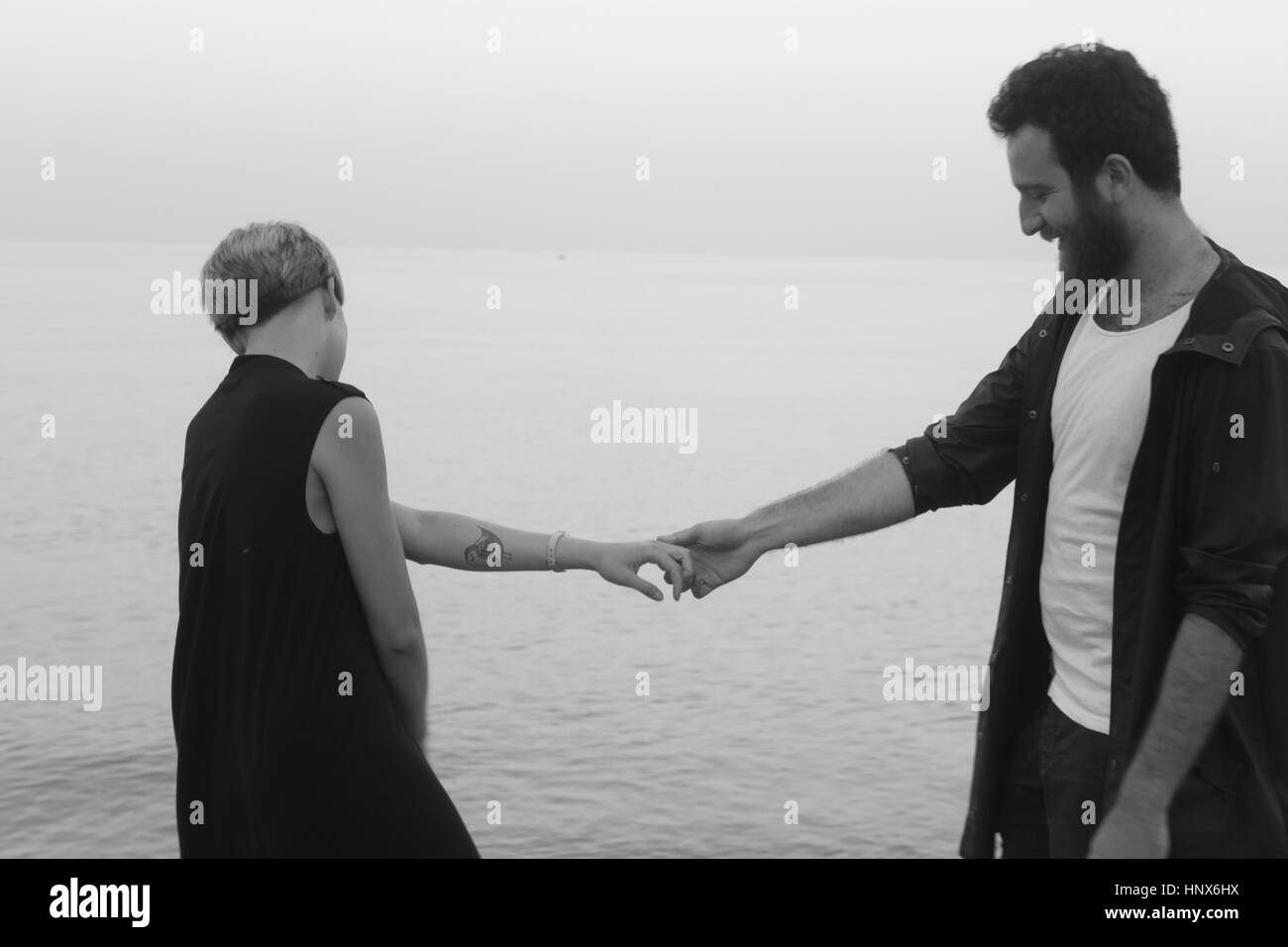 Junges Paar stand neben Meer, Hand in Hand Stockfoto