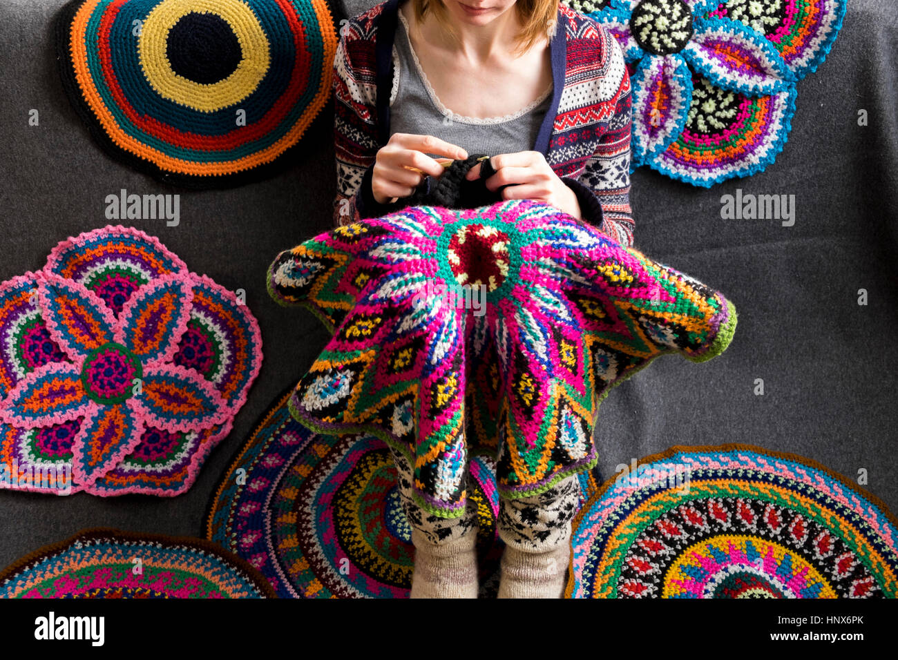 Blick auf Frau sitzt auf dem Boden zu häkeln, häkeln Kreise abgeschnitten Stockfoto