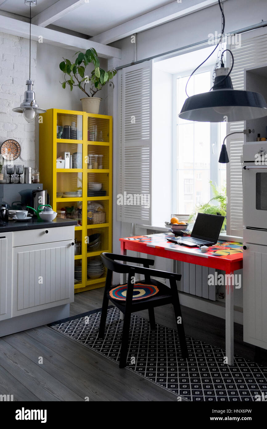Küche mit gelben Schrank und Laptop auf Tisch Stockfoto