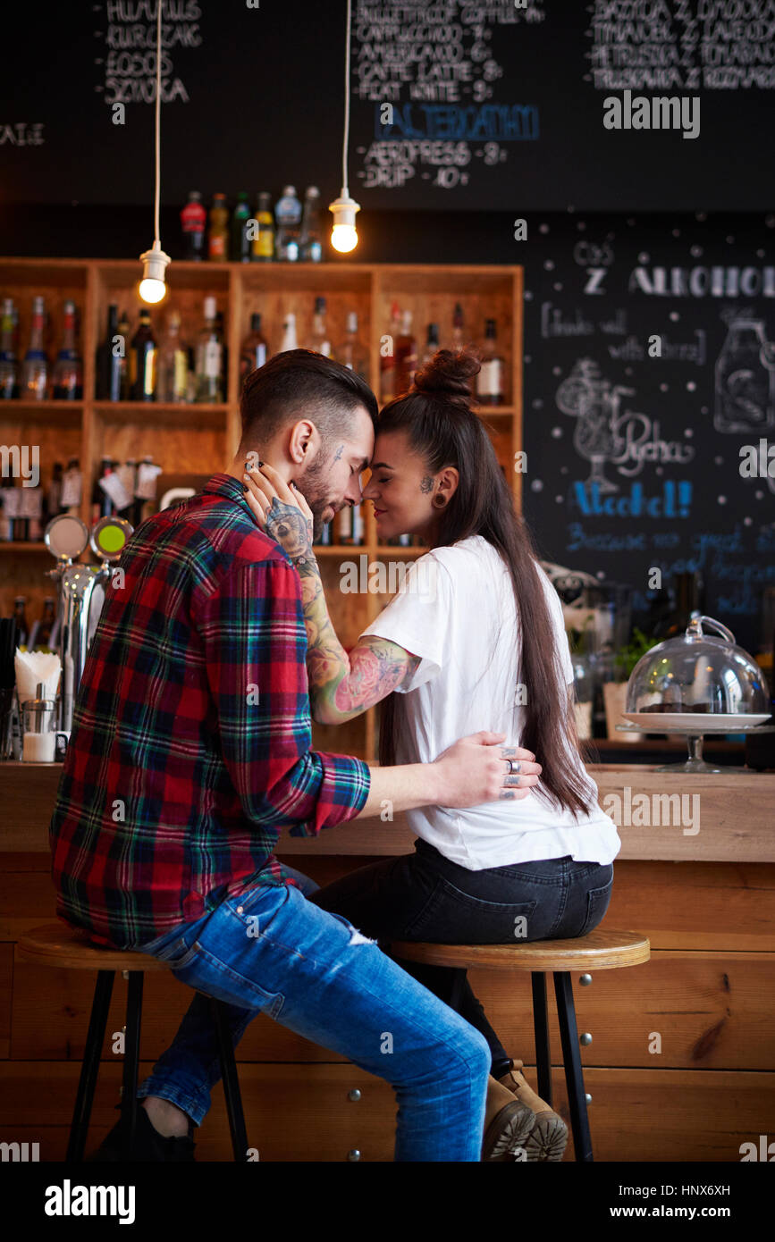 Paar auf Hockern in Coffee-Shop von Angesicht zu Angesicht lächelnd Stockfoto