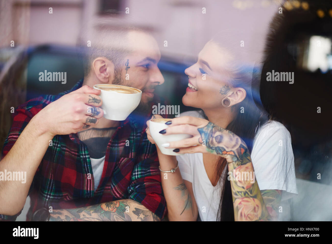 Blick durch die Fenster des Paares im Coffee-Shop von Angesicht zu Angesicht lächelnd Stockfoto