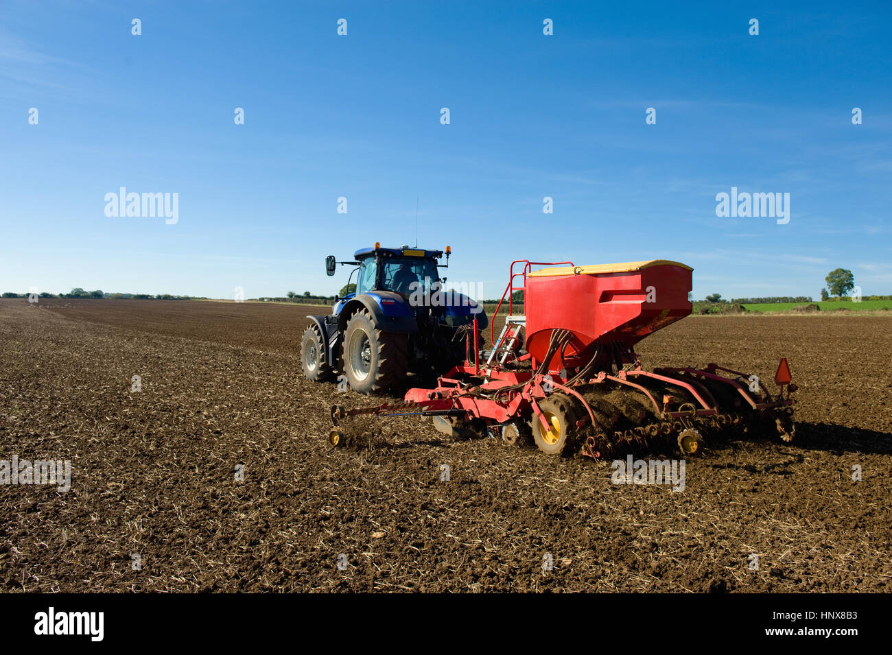 Rückansicht des Bauer Traktor fahren mit Sämaschine in Acker im Frühjahr Stockfoto
