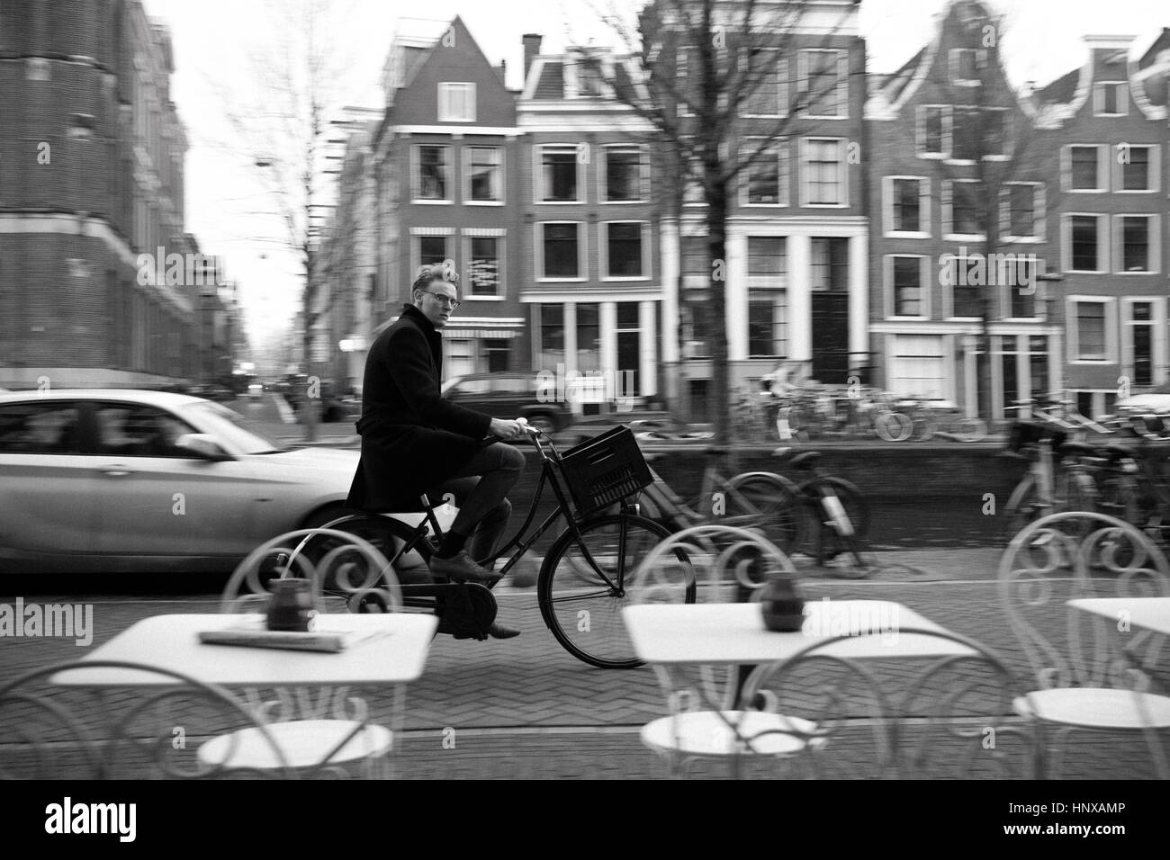 Street Scene der Mann auf dem Fahrrad Schuß von Cafe in Amsterdam, Holland. Stockfoto