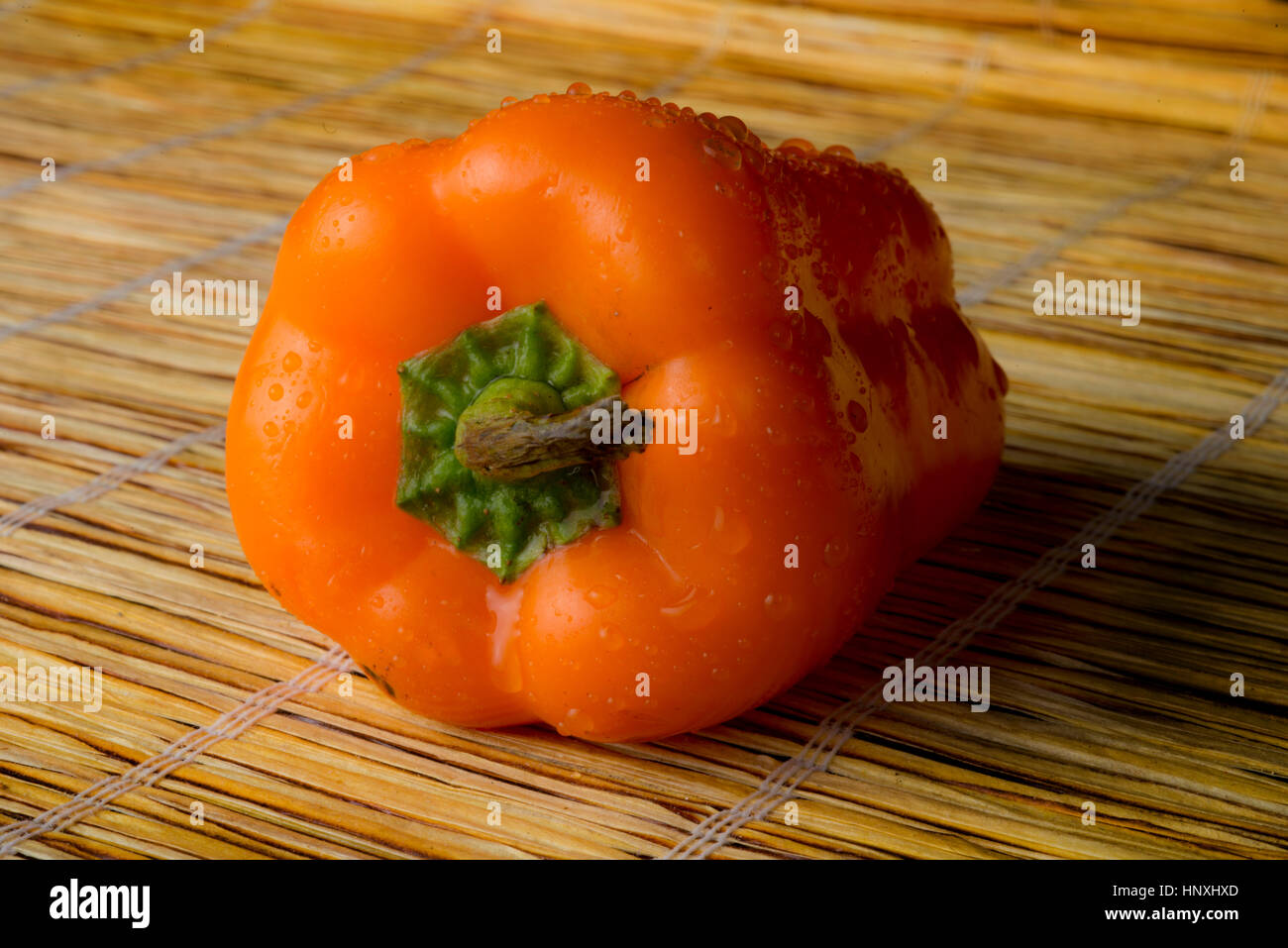 orange Paprika auf eine Strohmatte Stockfoto