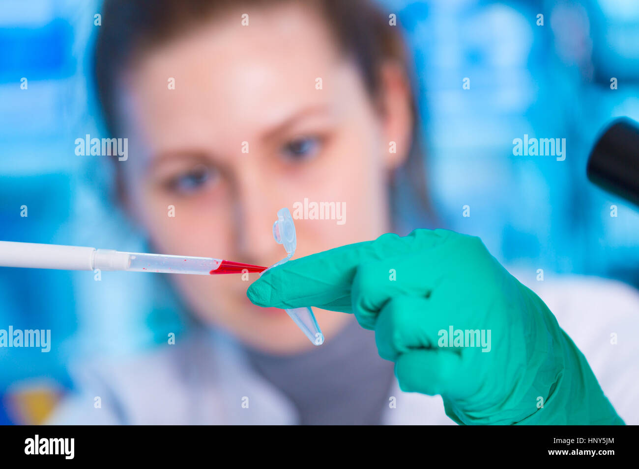 Ein junger Chemiker Reagenzglas mit Flüssigkeit während chemisches Experiment zu halten.  Assistent im Labor mit der Pipette Forschung von Krebsstammzellen.  Weiblich Stockfoto