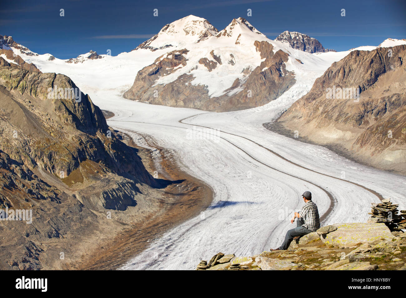Junger Mann sitzen und genießen Sie einen majestätischen Blick auf den Aletschgletscher, den größten gracier in Alpen und UNESCO starten vom Eggishorn, Wallis, Schweiz Stockfoto