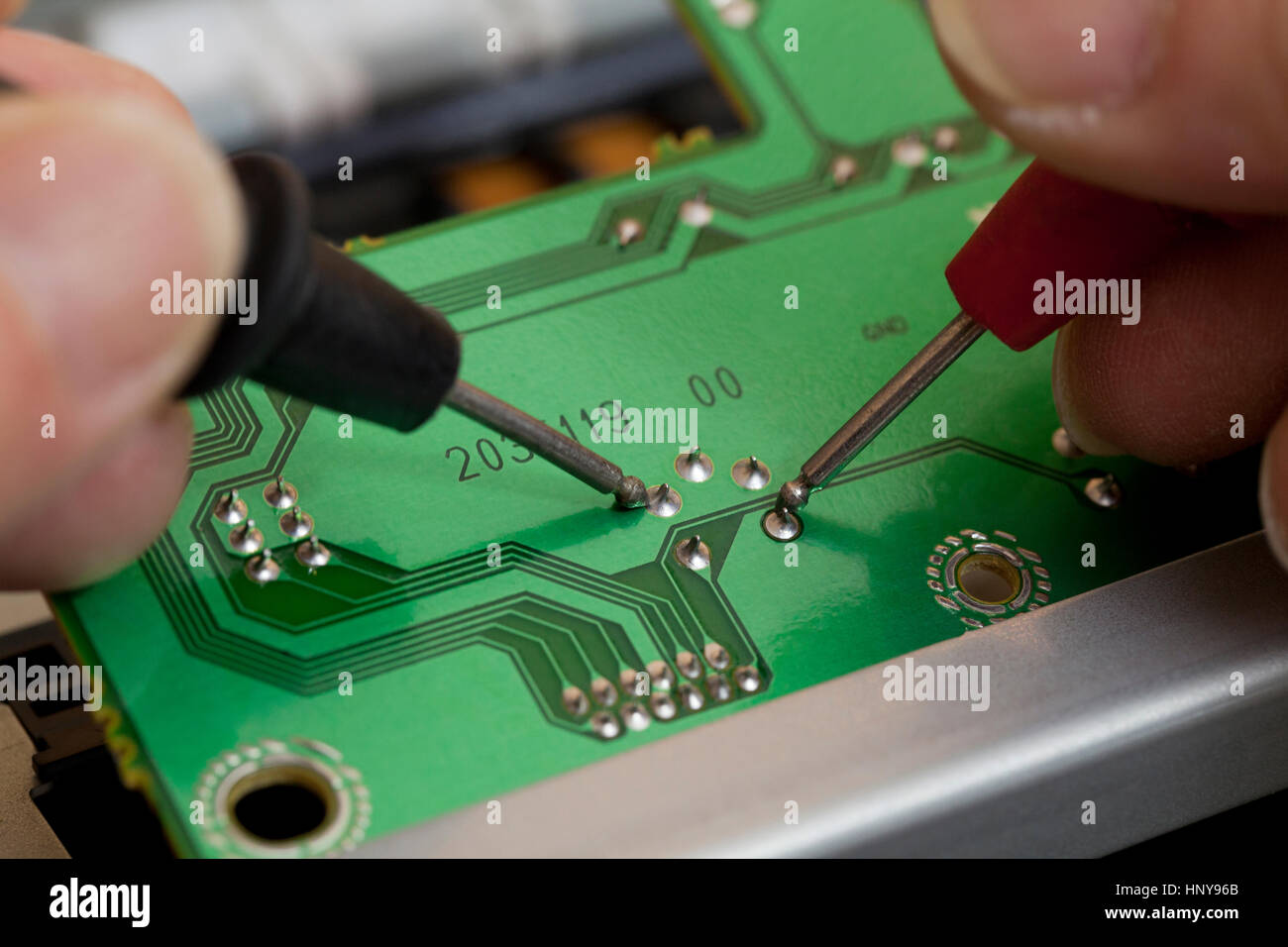 Techniker testen Kontaktstellen auf Leiterplatte mit einem Voltmeter (Elektronik Reparatur) - USA Stockfoto