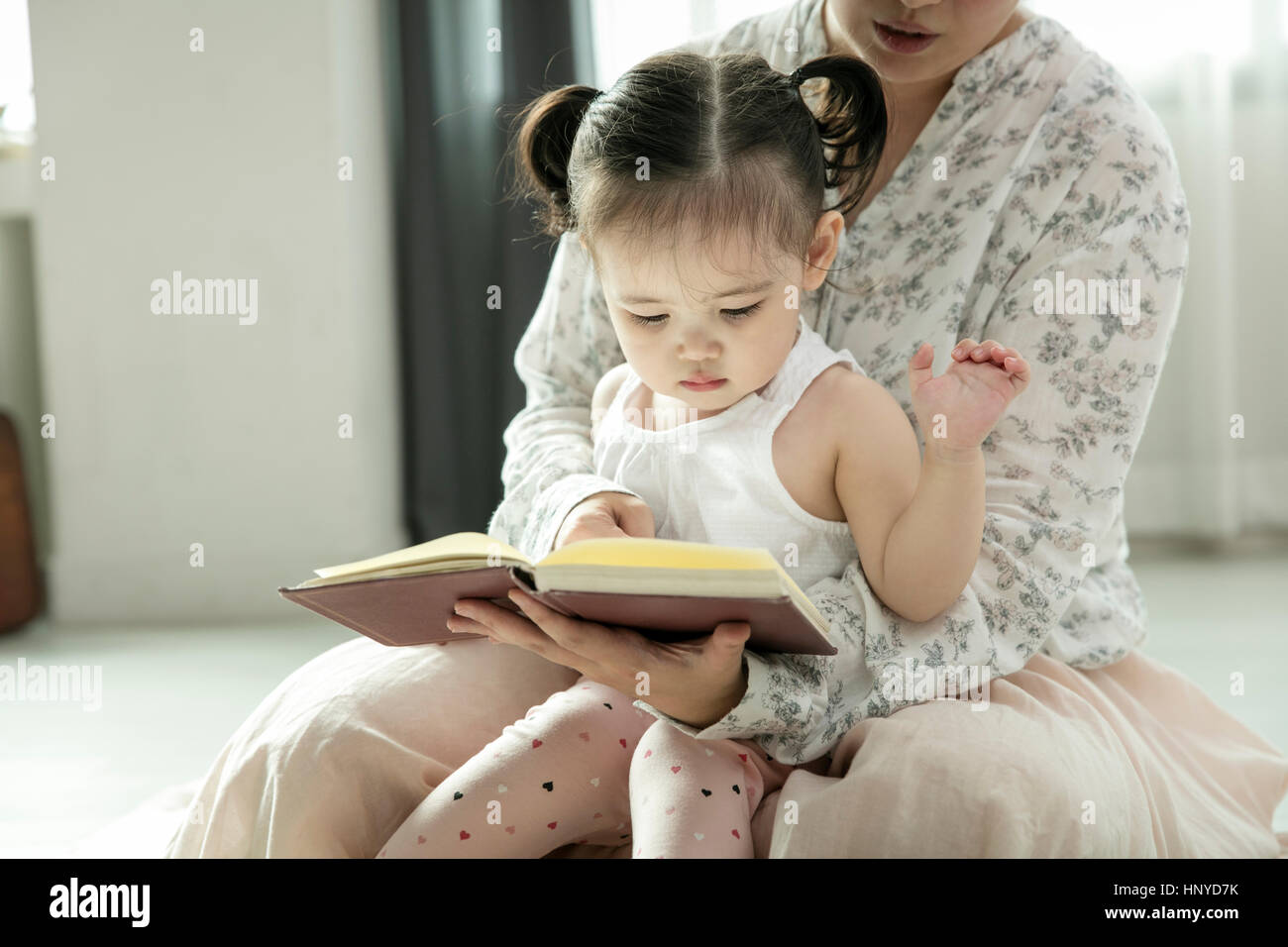 Liebevolle Mutter und Baby Tochter Lesung Bilderbuch Stockfoto