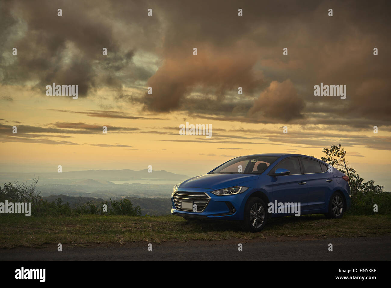 Eine moderne geparkten blauen Auto auf ziemlich Sonnenuntergang Dämmerung Hintergrund Stockfoto