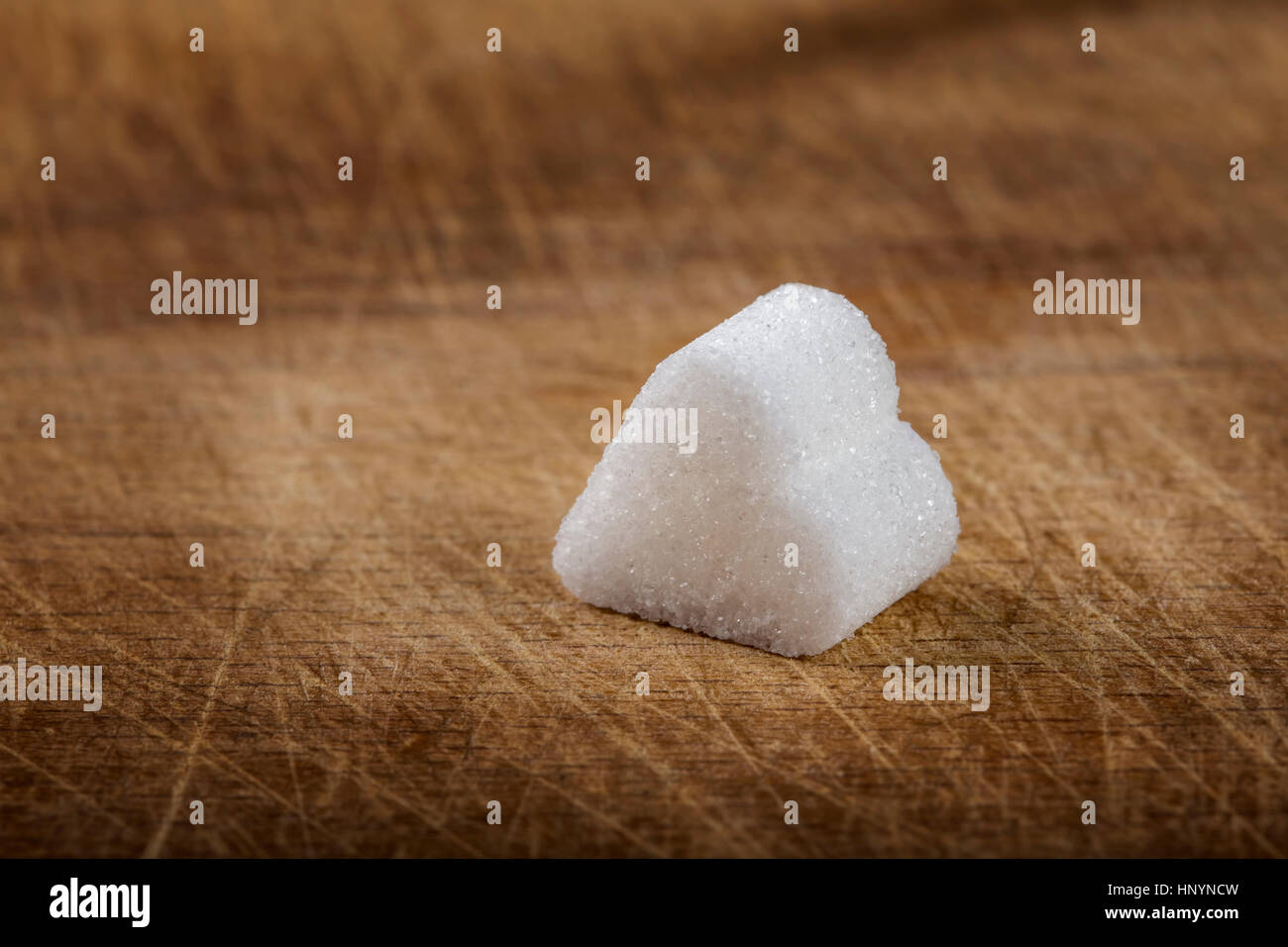 Ein Stück Würfelzucker in Herzform über hölzerne Hintergrund mit Textfreiraum Stockfoto