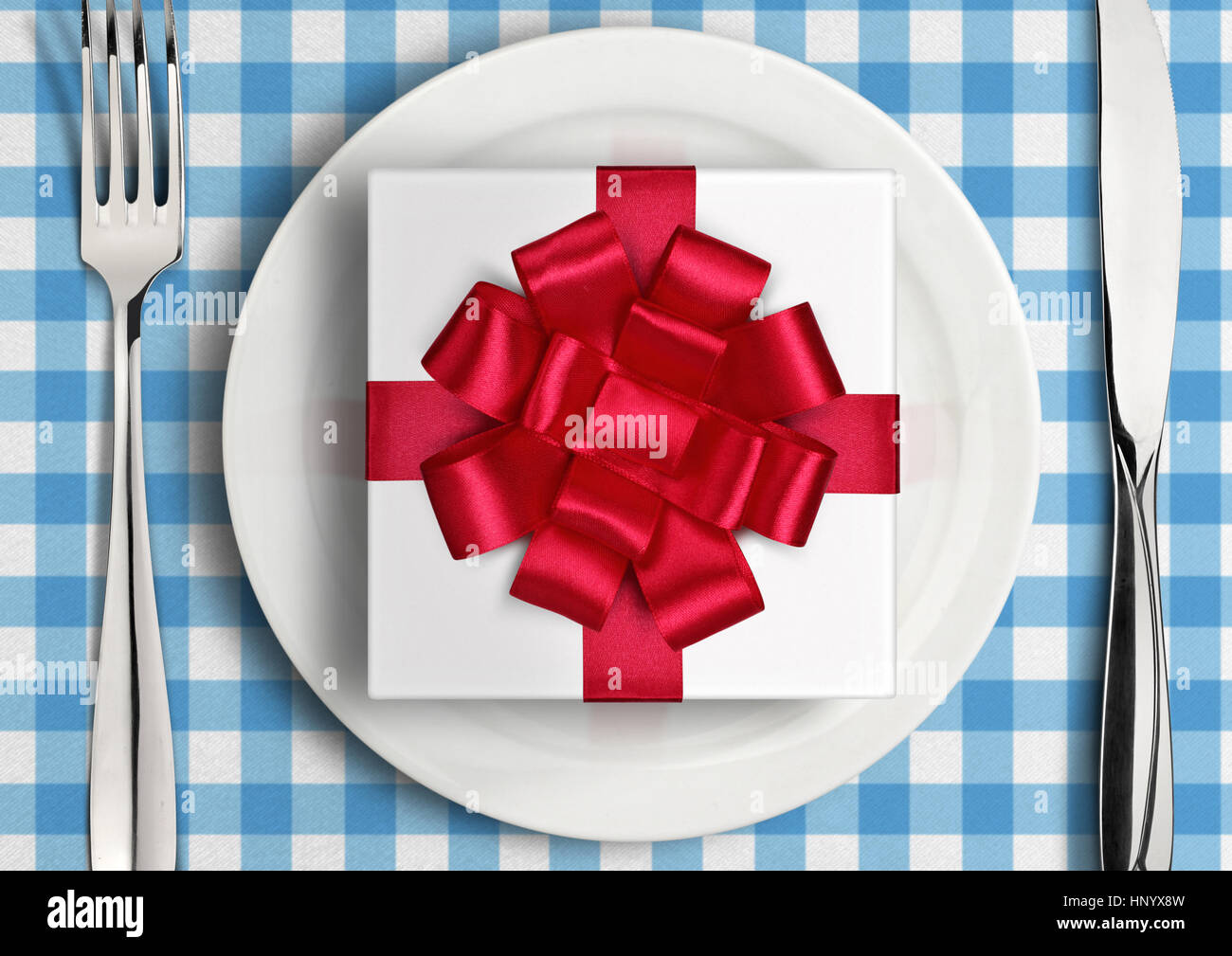 Romantisches Dinner-Konzept, Geschenk mit Schleife auf Platte Stockfoto