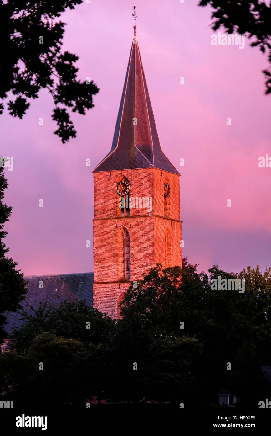 Abendsonne beleuchtet den Kirchturm mit einem orangefarbenen Schein Stockfoto