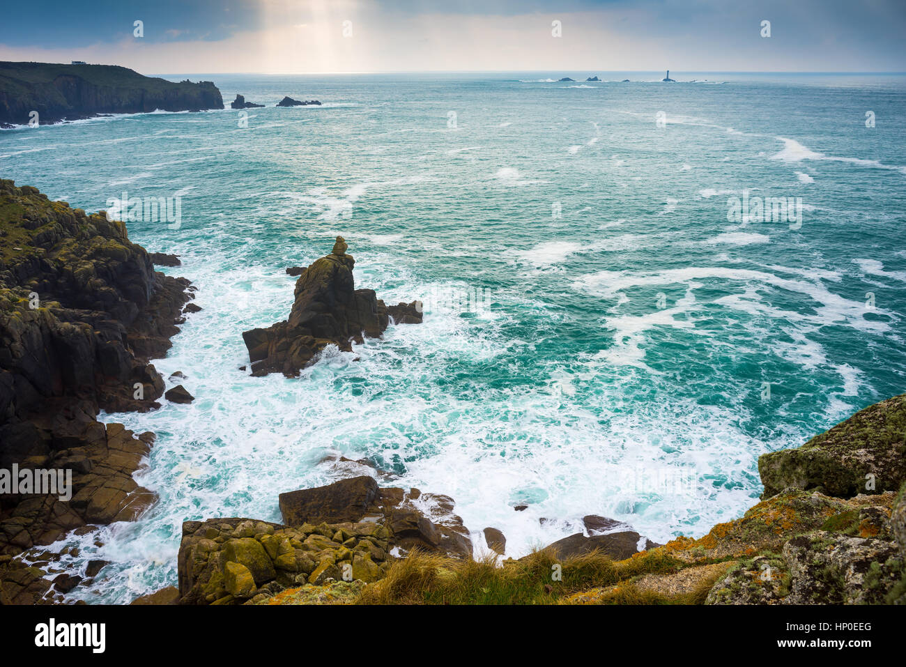 Mit Blick auf Wellen und die Irish Lady Felsformation Sennen Cove mit Lands End Cornwall in der Ferne. Stockfoto