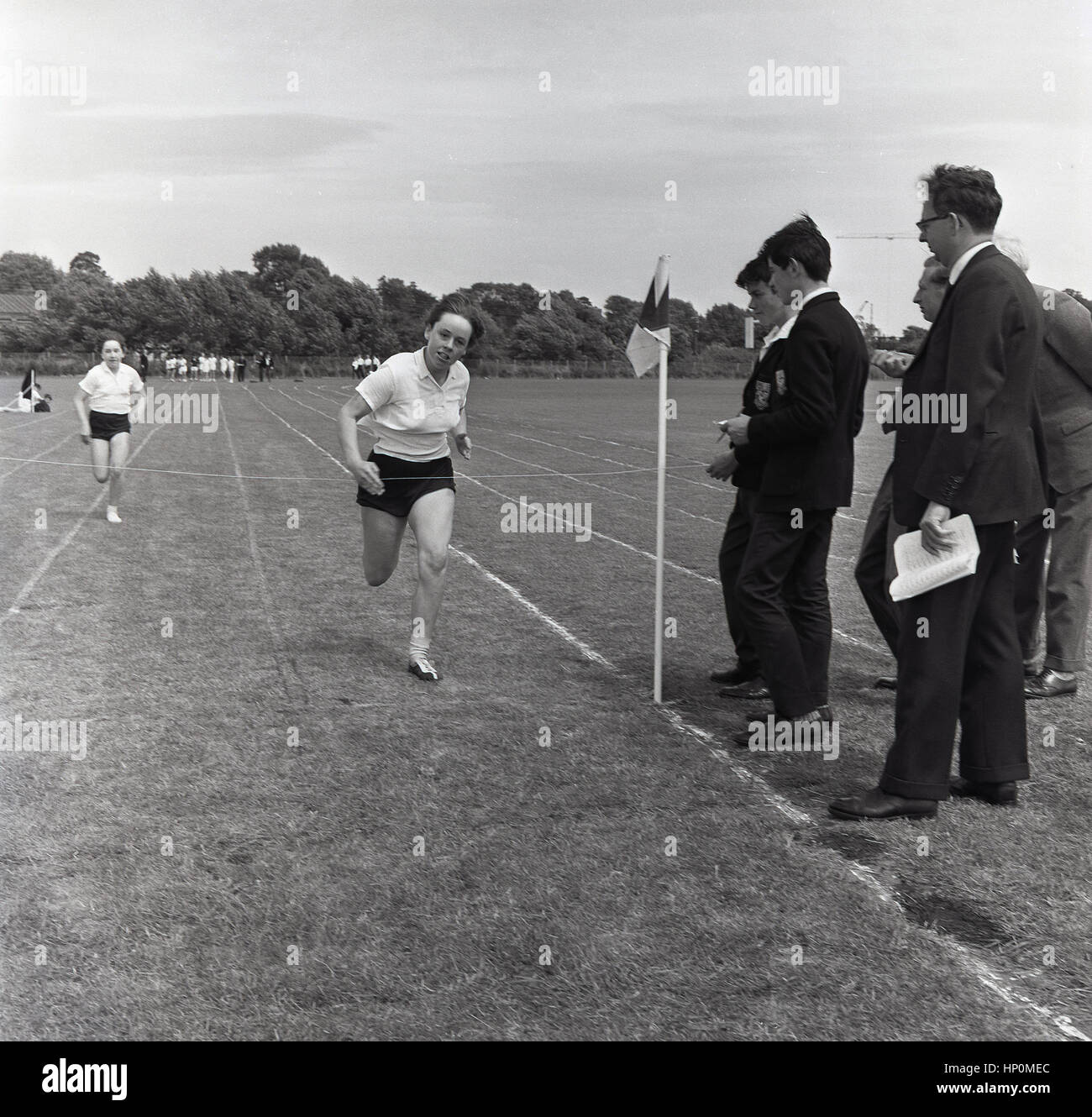 1960er-Jahren, historische, entschlossen Schulmädchen vor der Ziellinie in einem 100 Hof Rennen außerhalb auf einer Strecke von Grass. Stockfoto