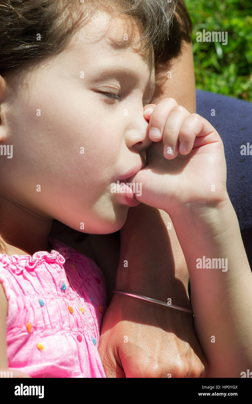 Kleines Mädchen schlafend auf Mutters Schoß, Daumenlutschen, beschnitten Stockfoto